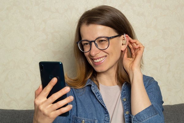 A woman using a hearing aid talks on a smartphone webcam