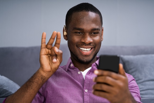 A black man who is deaf uses sign language on a mobile device