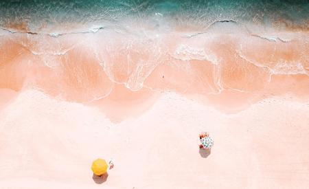 overhead view of a beach with two lounge chairs and umbrellas