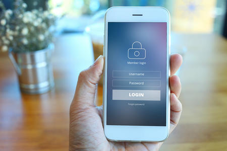 Person holding up mobile phone with login screen showing